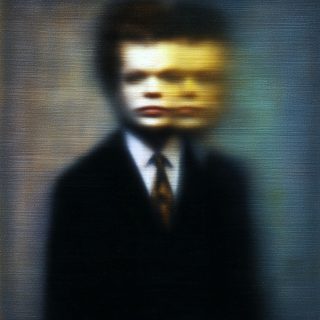 A young man’s portrait blurred almost to abstraction, a streak of gold light crossing the smeared face.