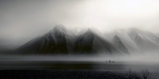 Layered mountains half-dissolved in fog, their ridgelines barely showing.