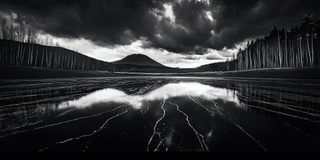 Dark mountains held in a perfectly still mirror of water.