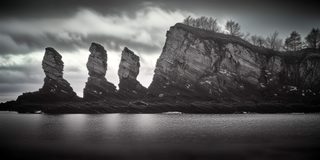 A row of jagged stone fins rising like teeth from the water.