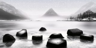 A row of stones standing in still water at the edge below the hills.