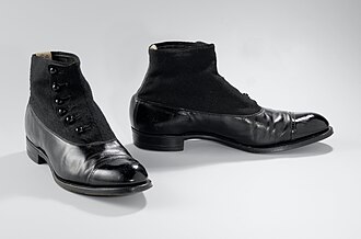 a pair of worn leather ankle boots, laces slack, cracked at the toe