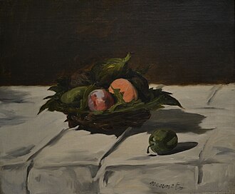 a shallow wicker basket packed with fruit, straw padding, a bottle laid among it