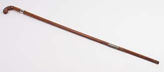 a slender wooden walking cane, tapering, with a worn handle and a metal ferrule