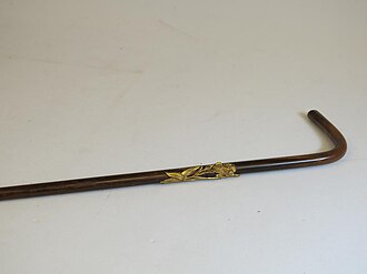 a stout ash walking stick, bark-flecked, one end cut square